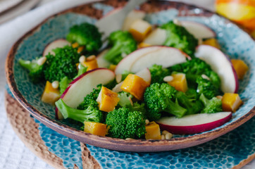 Salad with baked pumpkin, apple, broccoli and pine nuts. Ceramic plates handmade. Rustic style.
