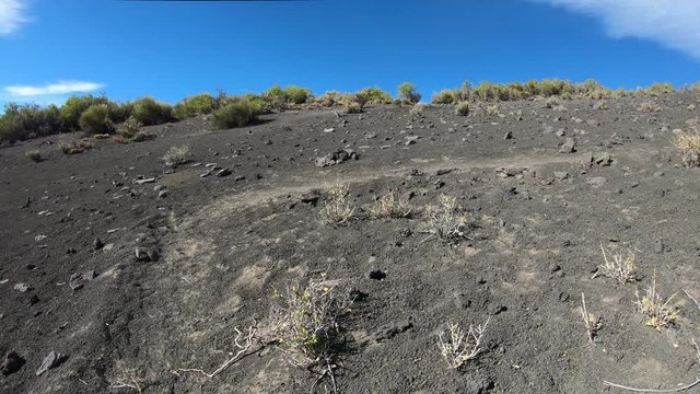 Walking over volcanic soil, debris, towards malacara volcano. Traveling through gravel trail. Background of mountian. Mendoza, Argentina.
