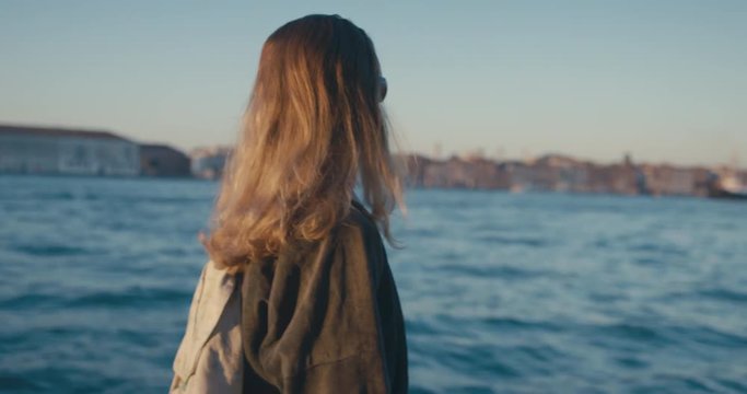 Woman walking by rive rin Venice at sunrise