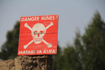 White skull-and-crossbones symbol on a red sign warning of the danger of landmines, Democratic...