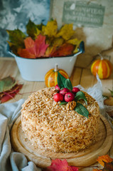 autumn cake decorated with paradise apples. Autumn still life with cake. Traditional Russian honey cake. Honey cake with sour cream, prunes and walnuts.