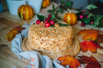 autumn cake decorated with paradise apples. Autumn still life with cake. Traditional Russian honey cake. Honey cake with sour cream, prunes and walnuts.