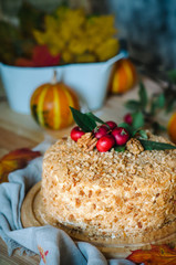 autumn cake decorated with paradise apples. Autumn still life with cake. Traditional Russian honey cake. Honey cake with sour cream, prunes and walnuts.