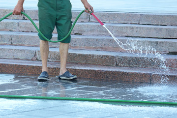 worker from a hose watering the city street
