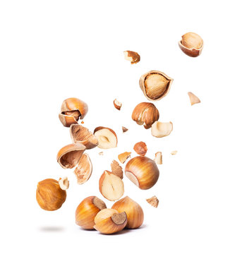 Сracked hazelnuts fall down isolated on white background