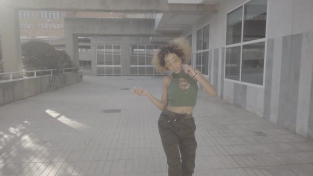 Latin American woman poses on camera dancing in town.