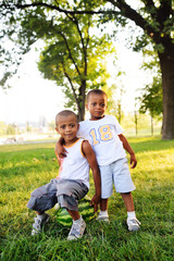 Fototapeta premium two happy black African American baby boy sitting on a big watermelon smiling on a Park background on a summer day.