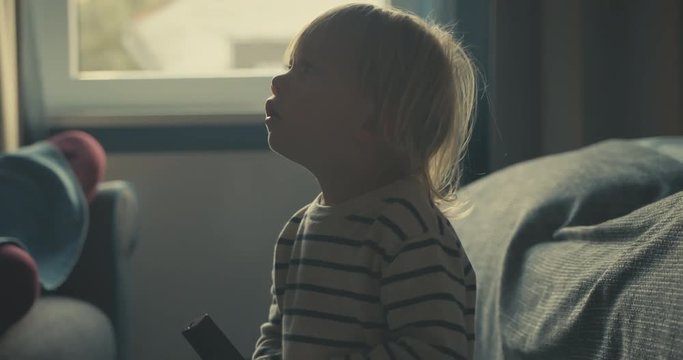 Little toddler using remote control in hotel room