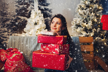 Portrait of attractive caucasian woman in grey dress holding pile of red wrapped christmas gifts...
