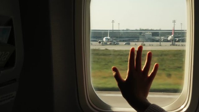 Kid s hand touching airplane window, close up. Silhouette of a child's palm against the background of a window in an airplane. The concept of safety of flights.