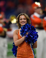 Young college cheerleader performing at a college football game