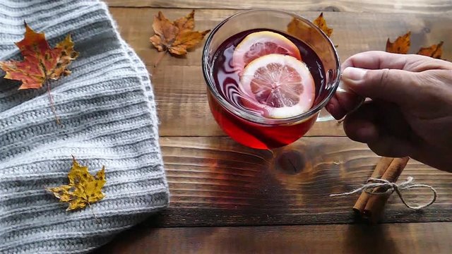 Putting a cup of tea with lemon on table with autumn decoration  slow motion