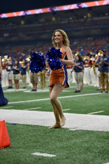Young college cheerleader performing at a college football game