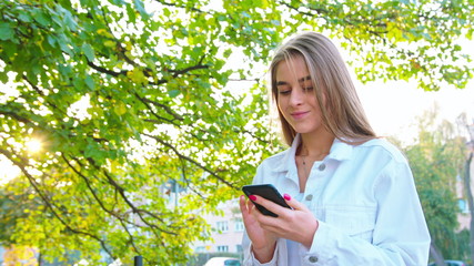 Woman texting on smartphone looking happy outside, Caucasian girl in her 20s happily texting on...