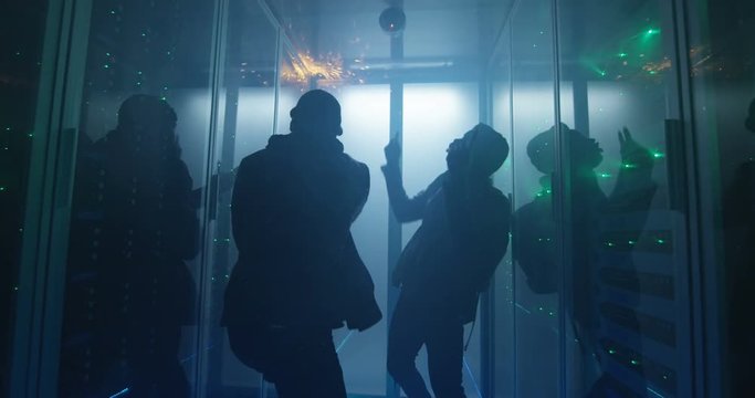 Medium shot of two hackers arguing in a smoke-filled corporate data center trying to escape