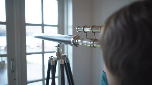 Woman approaches old telescope and looks through it