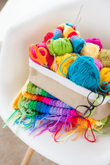 Basket with colored, bright yarn for knitting on a white armchair. Crochet.