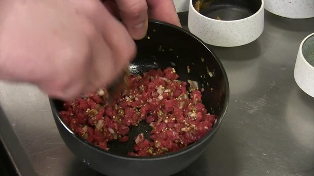 Chef preparing tatar in a bowl in the kitchen of a restaurant