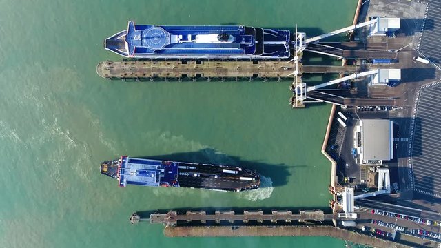 Aerial top down view of ferry moving backwards to dock and embark this vessel carries lorries cars and passengers across body of water ferries form part of the public transport systems 4k resolution