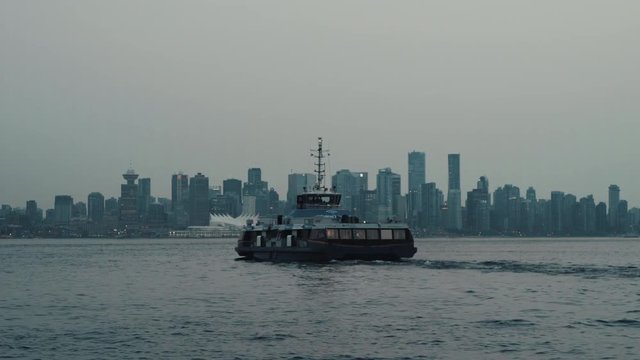 Sea bus leaving Lonsdale Quay and cruising towards Vancouver downtown in dusk