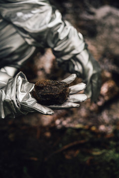 Spaceman exploring nature, holding soil