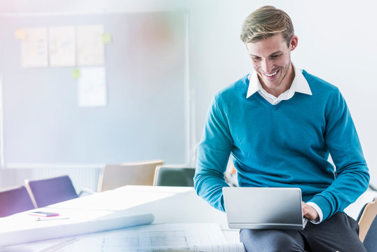 Smiling businessman using mini laptop in office