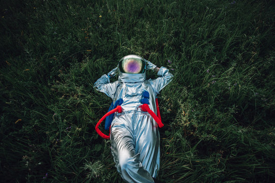 Spaceman exploring nature, relaxing in meadow