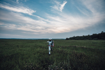 Spaceman exploring nature, walking in meadow