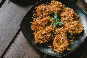 Delicious Asian - Asia eating Thai food. Crispy shrimp with sweet tamarind sugar sauce. Served with chili fried, crispy onion and green vegetable fried on a plate and wooden table background.