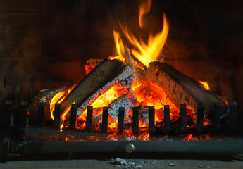 Fototapety  Wood burning in a cozy fireplace at home in interior. Fireplace as a piece of furniture. Christmas New Year concept decorations.
