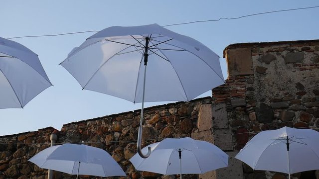 Umbrellas hanging in the sky being moved by the air