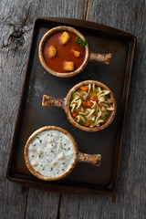 Overhead view of three different bowls of soup on a baking sheet