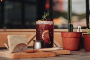 Iced tea with lemon and raspberry in tall glasses and strawberry crepe cake on rustic table decorated with cactus tree