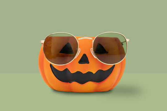 Halloween pumpkin with glasses on green background. Halloween minimal idea concept