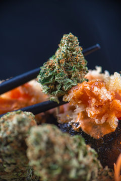 Cannabis buds served on a sushi plate with smoke and chopsticks on a dark background