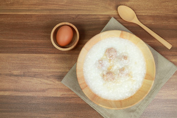 rice porridge with meatball, egg and spoon on wooden table