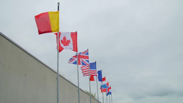 Allied Flags Flying High On Masts Above The Beaches Of Normandy, Flags Of Canada, United Kingdom, France, United States Of America, The Netherlands And Norwegian On Masts Near Utah Beach Museum