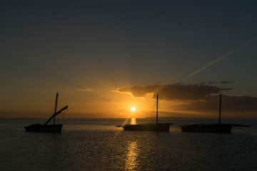 Fototapeta na wymiar Three Boats Silhouetted by the Sunrise in Mozambique, Africa