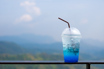 Blue Hawaii soda tropical drink on clear sky over mountain forest. Summer holiday relax background with copy space.