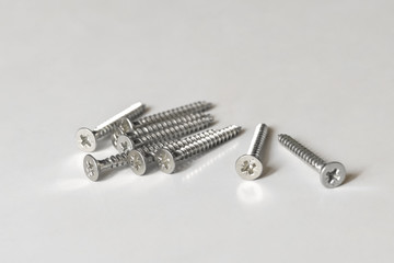 Several silver galvanized screws for construction work on the surface of the light table