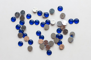 A handful of shiny blue sequins for needlework, lying on the light surface of the table. Top view