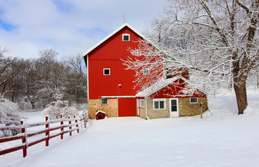 Agriculture and rural life at winter background.Rural landscape with red barn, wooden red fence and trees covered by fresh snow in sunlight. Scenic winter view at Wisconsin, Midwest USA, Madison area.