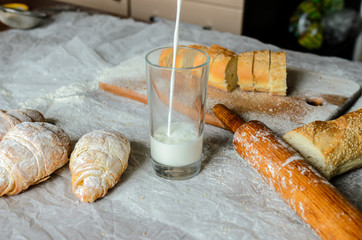 Milk is poured into a glass, bread, croissants