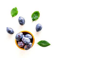 Blue plum for dessert. Purple plum and leaves pattern on white background top view copy space