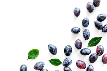 Blue plum for dessert. Purple plum and leaves pattern on white background top view copy space