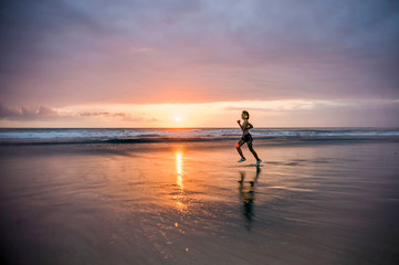 silhouette of fit and athletic Asian Chinese sporty woman running on beautiful beach doing jogging workout on sunset in fitness healthy lifestyle and summer outdoors activity