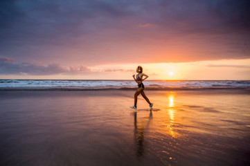 Fototapeta premium silhouette of fit and athletic Asian Chinese sporty woman running on beautiful beach doing jogging workout on sunset in fitness healthy lifestyle and summer outdoors activity