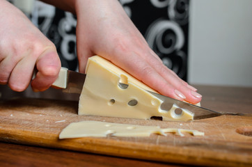 Slicing cheese on a wooden board.