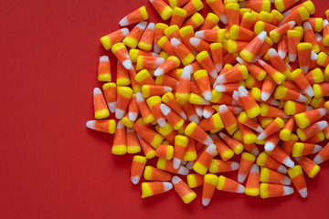 Big pile of Halloween candy corn on an orange background
