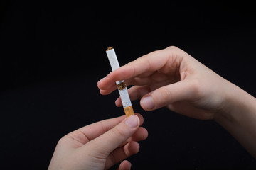 Hand is breaking a cigarette on black background